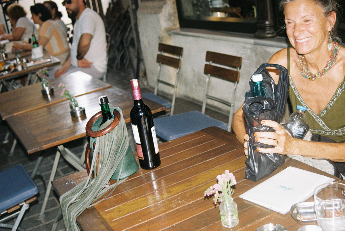 Both wine bags on a café table with a bottle of red wine